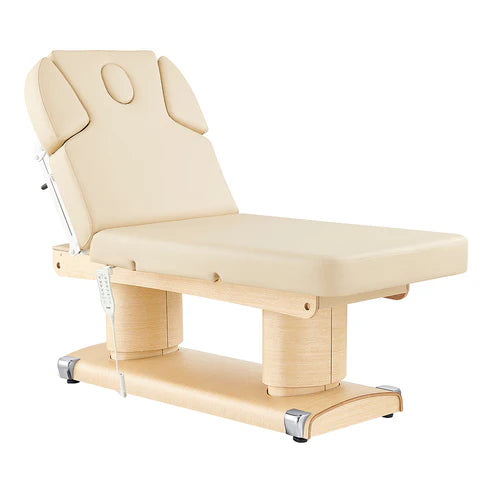 Luxi 4-motor electric medical spa treatment bed in premium Beige upholstery, featuring dual column lift base, hand remote, integrated foot controller, and adjustable headrest with side cushions.