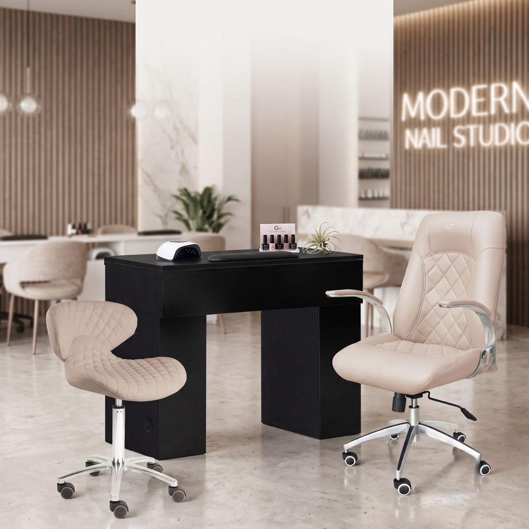 Modern black nail tech desk and beige tufted chairs in a professional salon studio setting.