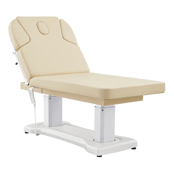 All-beige electric facial and medical spa table with an ergonomic contoured cushion, adjustable headrest, wired hand remote, and multi-button foot control pedal.