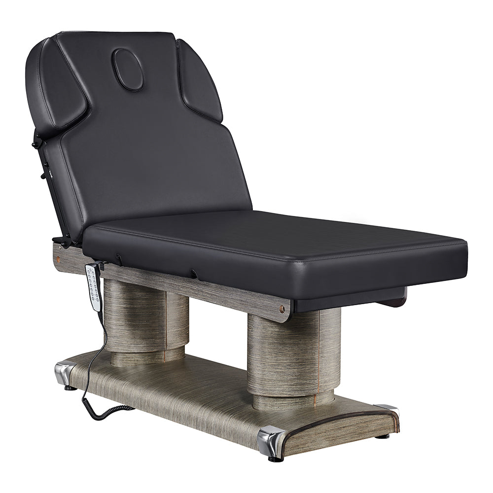 Luxi 4-motor electric medical spa treatment bed in premium Black upholstery, featuring dual column lift base, hand remote, integrated foot controller, and adjustable headrest with side cushions.